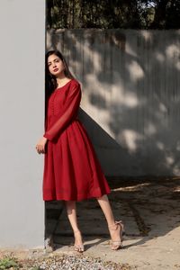 Portrait of young woman standing against wall