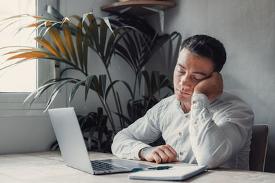 Side view of young woman using laptop at home