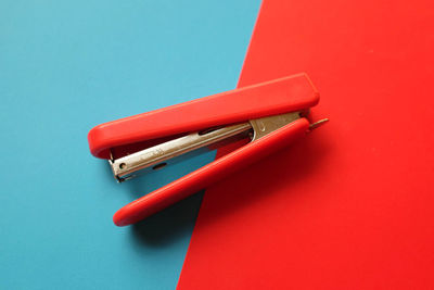 Flat lay a red hand stapler isolate on a colorful paper background