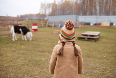 Unrecognizable little girl on horse farm back view