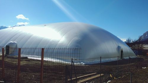 Large tent on field against blue sky