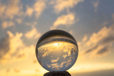 Close-up of crystal ball on glass against sunset sky