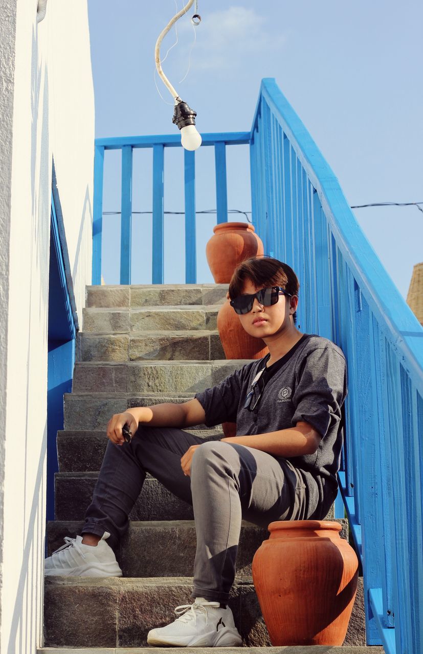 FULL LENGTH OF YOUNG WOMAN SITTING ON STEPS