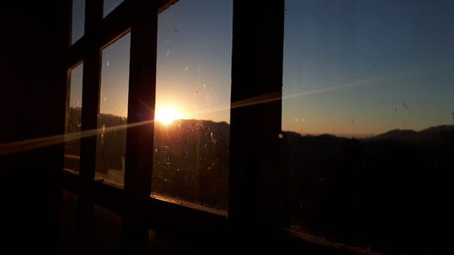 Close-up of window against sunset sky