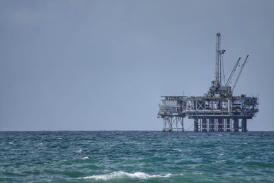 Scenic view of oil platform in sea against clear sky