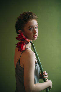 Portrait of young woman standing against gray background