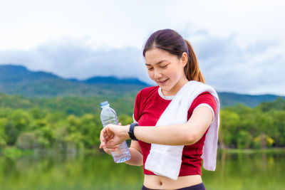 Mid adult woman holding smiling while standing against sky