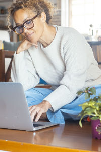 Young woman using laptop while sitting on table