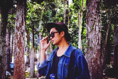 Young woman wearing hat standing against trees