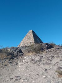 Low angle view of rock formations of a pyramid in desert against clear blue sky