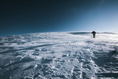 Man skiing on snowcapped mountain against clear sky