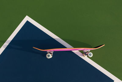 Side view of skateboard laying on a tennis court