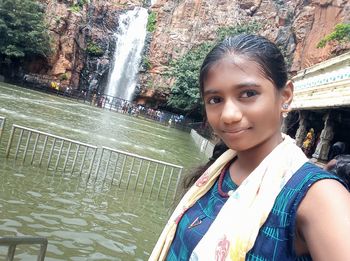 Portrait of smiling woman against waterfall