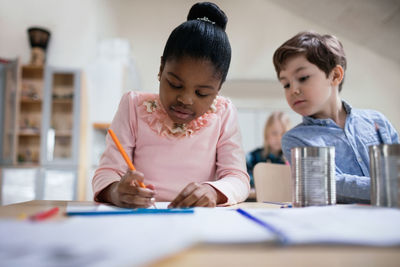 Boy in friend's paper while studying in classroom at table