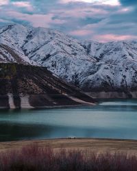 Scenic view of lake by snowcapped mountains against sky