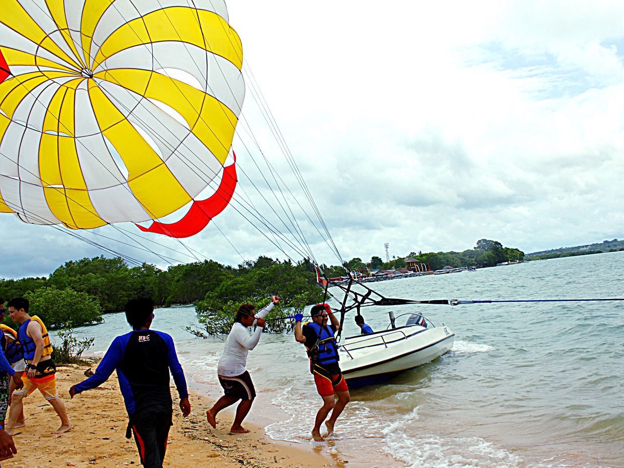 sky, leisure activity, multi colored, transportation, tree, sea, lifestyles, mode of transport, water, cloud, fun, cloud - sky, enjoyment, tourist, day, mid-air, outdoors, person, tourism, vacations, flying, cloudy, riverbank, non-urban scene