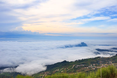 Scenic view of mountains against cloudy sky during sunset