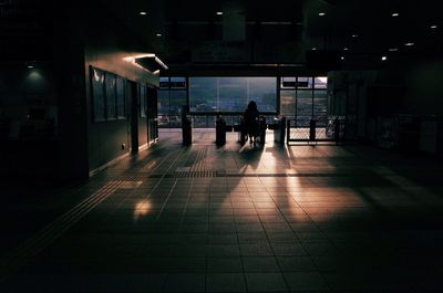 Silhouette people walking in illuminated building