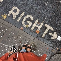 Low section of woman standing on wet footpath by text during monsoon