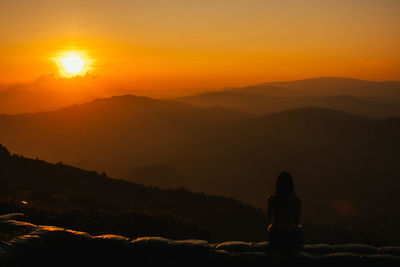 Silhouette people looking at mountains against sky during sunset