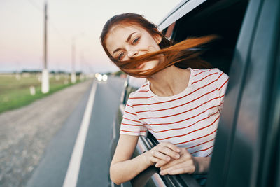 Portrait of woman standing by car