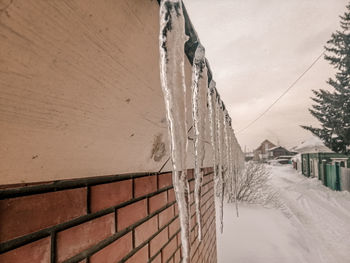 Snow covered wall by building against sky