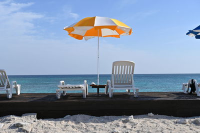 Deck chairs on beach against sky