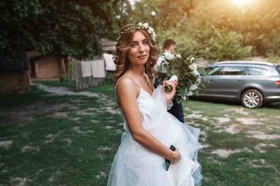 Portrait of bride holding bouquet while standing on field