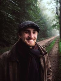 Portrait of smiling young man standing in forest