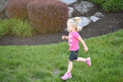 Full length side view of girl walking on grass