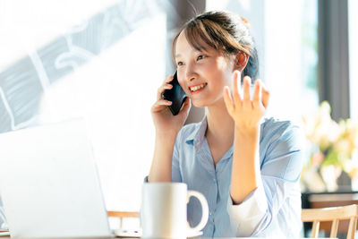 Businesswoman talking on phone while sitting on table