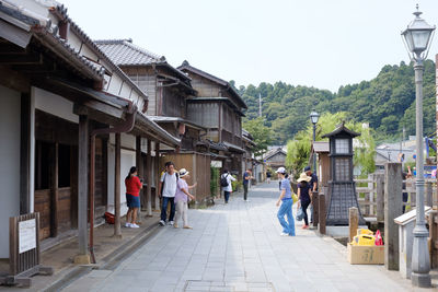 People walking on footpath amidst buildings in city