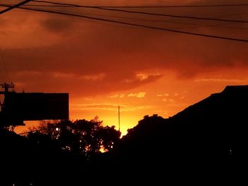 Silhouette trees against dramatic sky during sunset