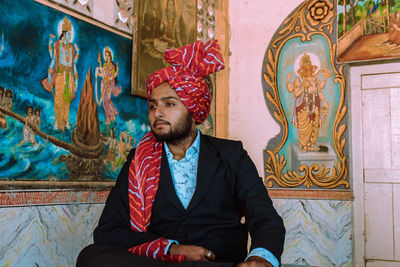 Young man looking away while sitting on chair 