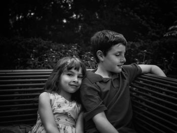 Portrait of girl sitting with brother on bench
