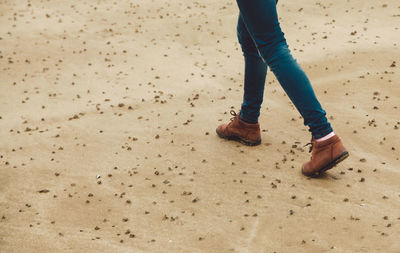 Low section of woman walking on sand