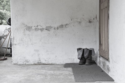 Man sitting on footpath against wall