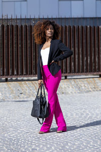 Woman looking away while standing on footpath in city