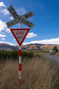 Road sign on field against sky