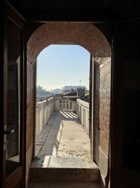 Corridor of historic building against clear sky seen through window