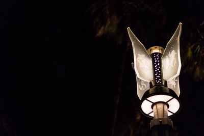 Low angle view of illuminated lamp against black background