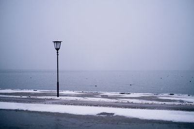 Street light on beach against clear sky