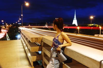Woman with light trails on road at night