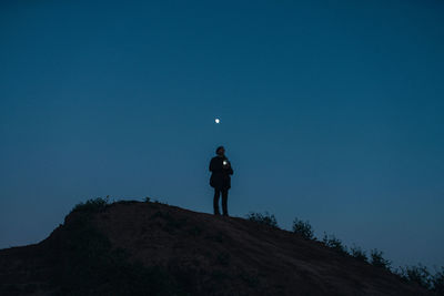 Silhouette man standing on hill against blue sky