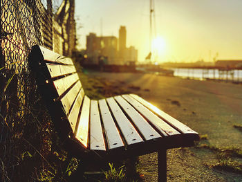 Empty bench in park during sunset