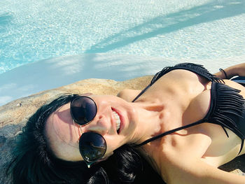 Low angle view of woman sunbathing next to the swimming pool