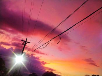 Low angle view of silhouette electricity pylon against sky during sunset