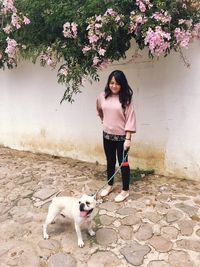 Woman standing with french bulldog on footpath