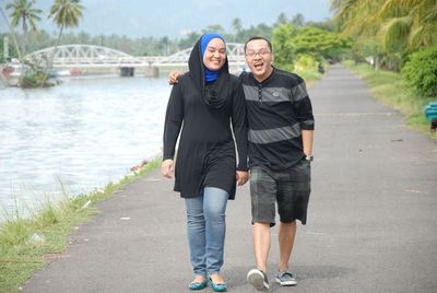 Portrait of smiling friends walking at lakeshore