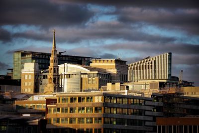 Buildings in city against cloudy sky